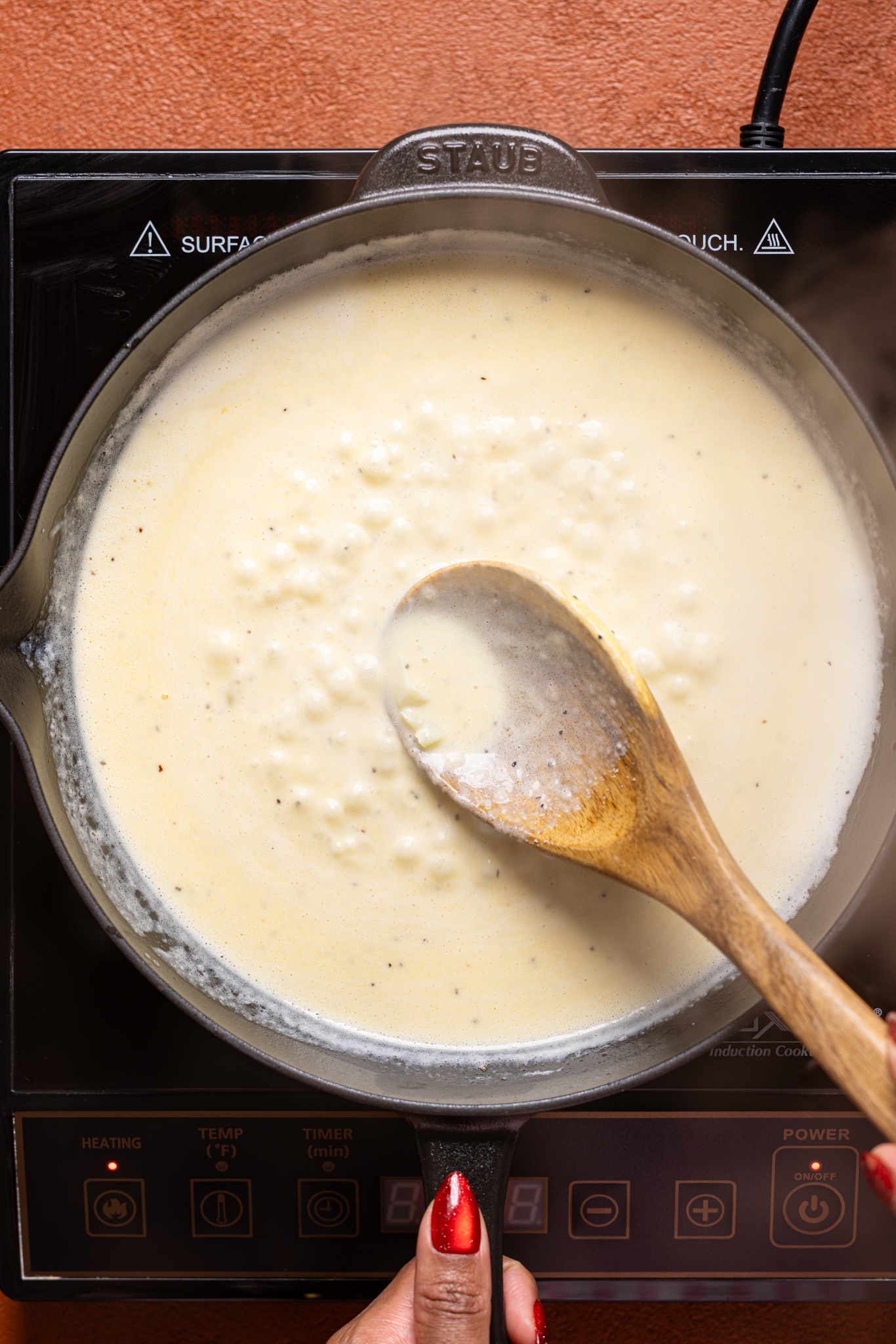 Alfredo sauce being cooked over the stovetop.