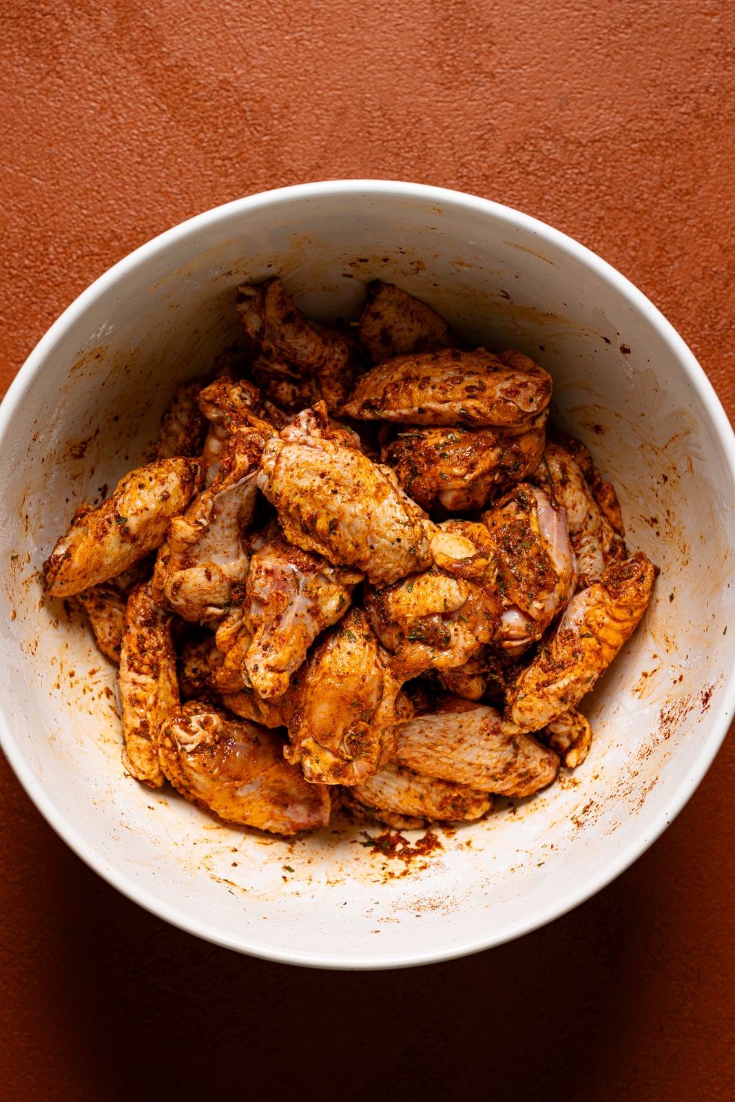 Seasoned chicken wings in a bowl.