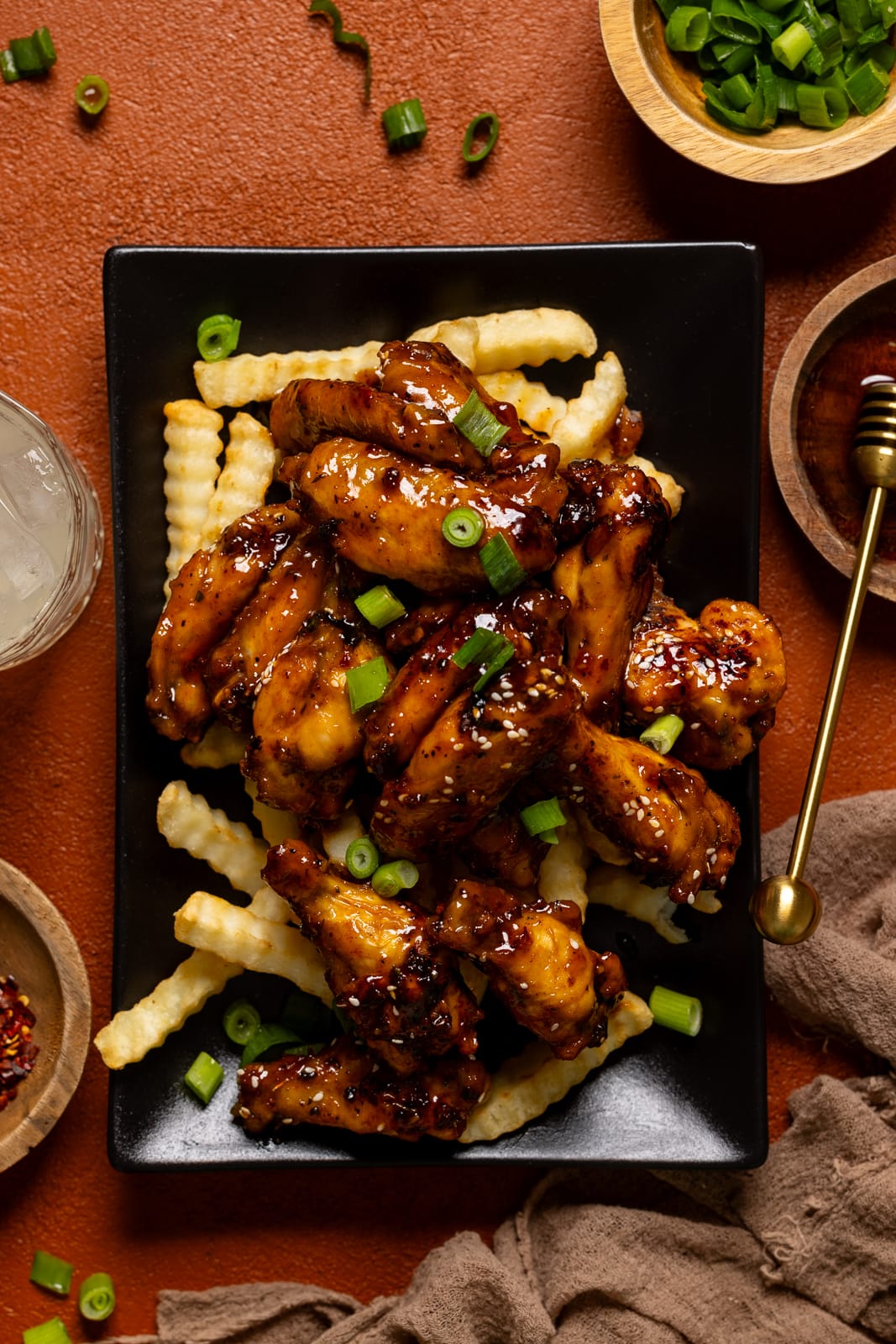 Up close shot of chicken wings on fries on a black platter.