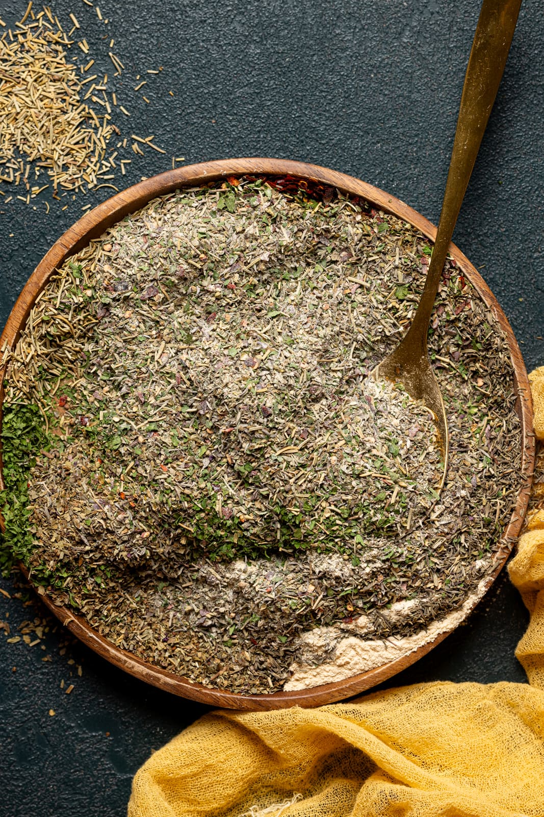 Stirred together seasonings on a brown wood plate with a spoon.