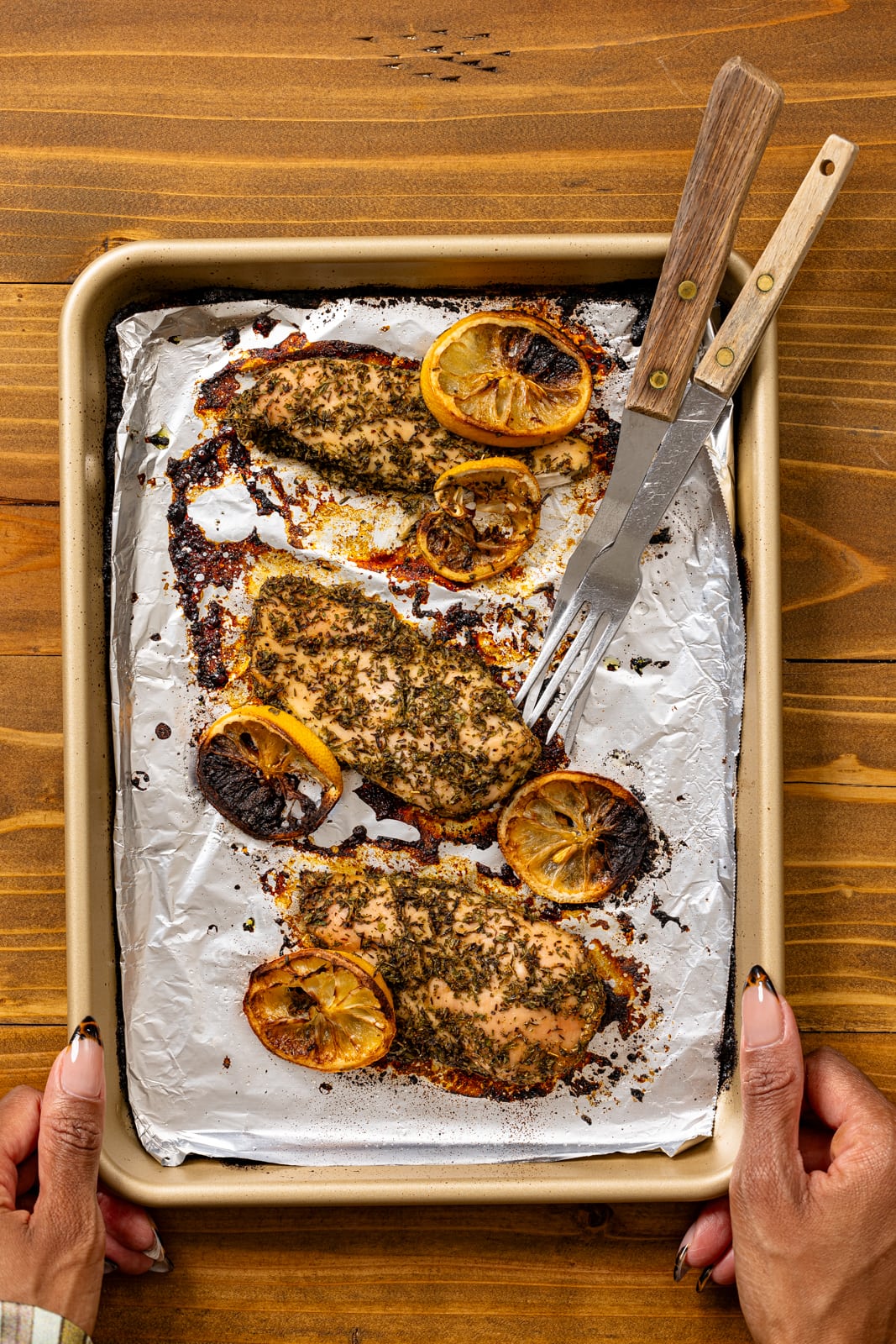 Roasted lemon chicken on a baking sheet with foil paper.