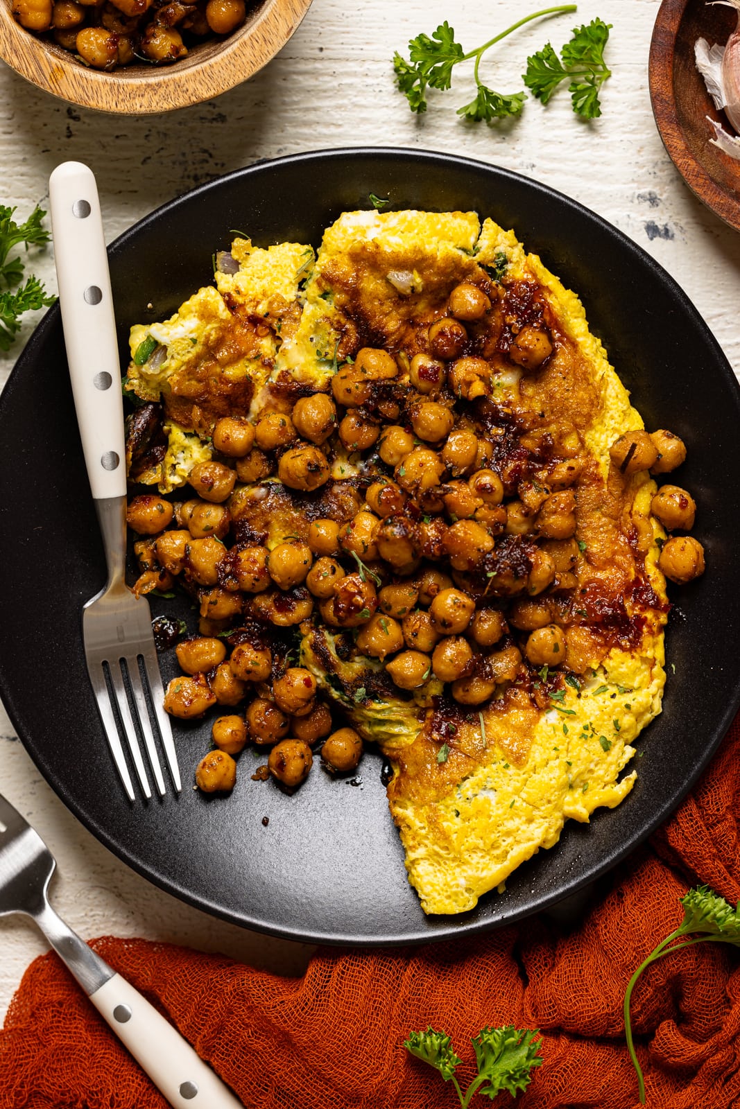 Up close shot of omelette in a black plate with two forks.