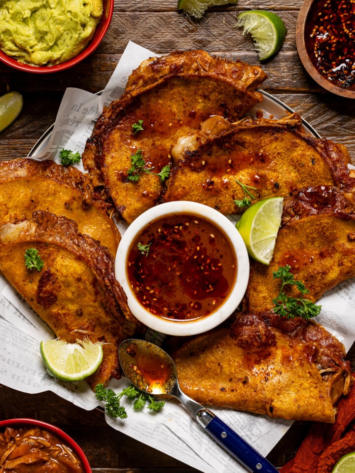 Tacos on a platter with dipping sauce and chili oil atop.