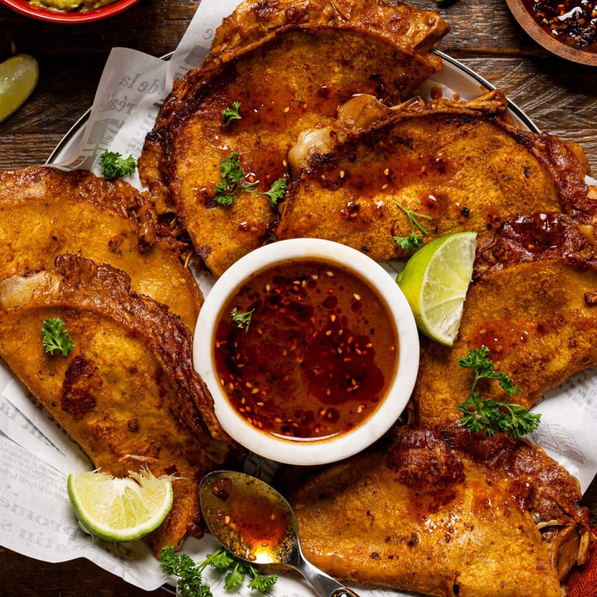 Tacos on a platter with dipping sauce and chili oil atop.