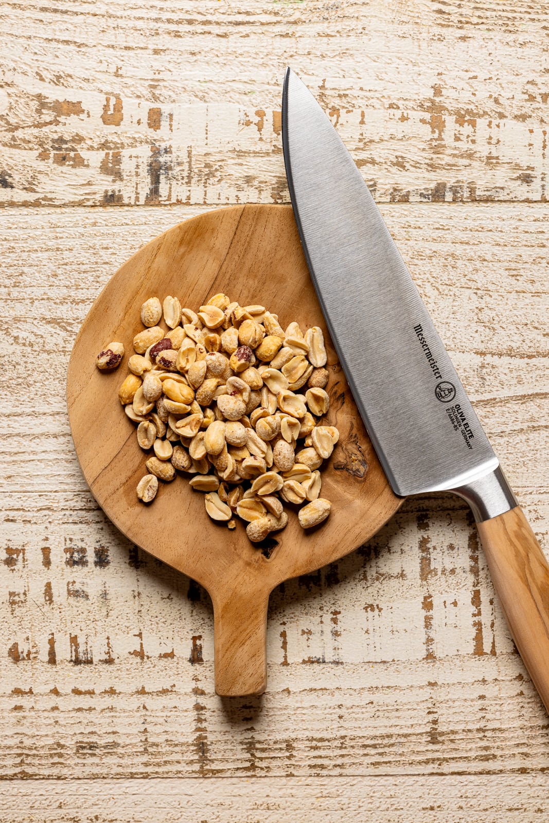 Chopped peanuts on a cutting board with a knife.
