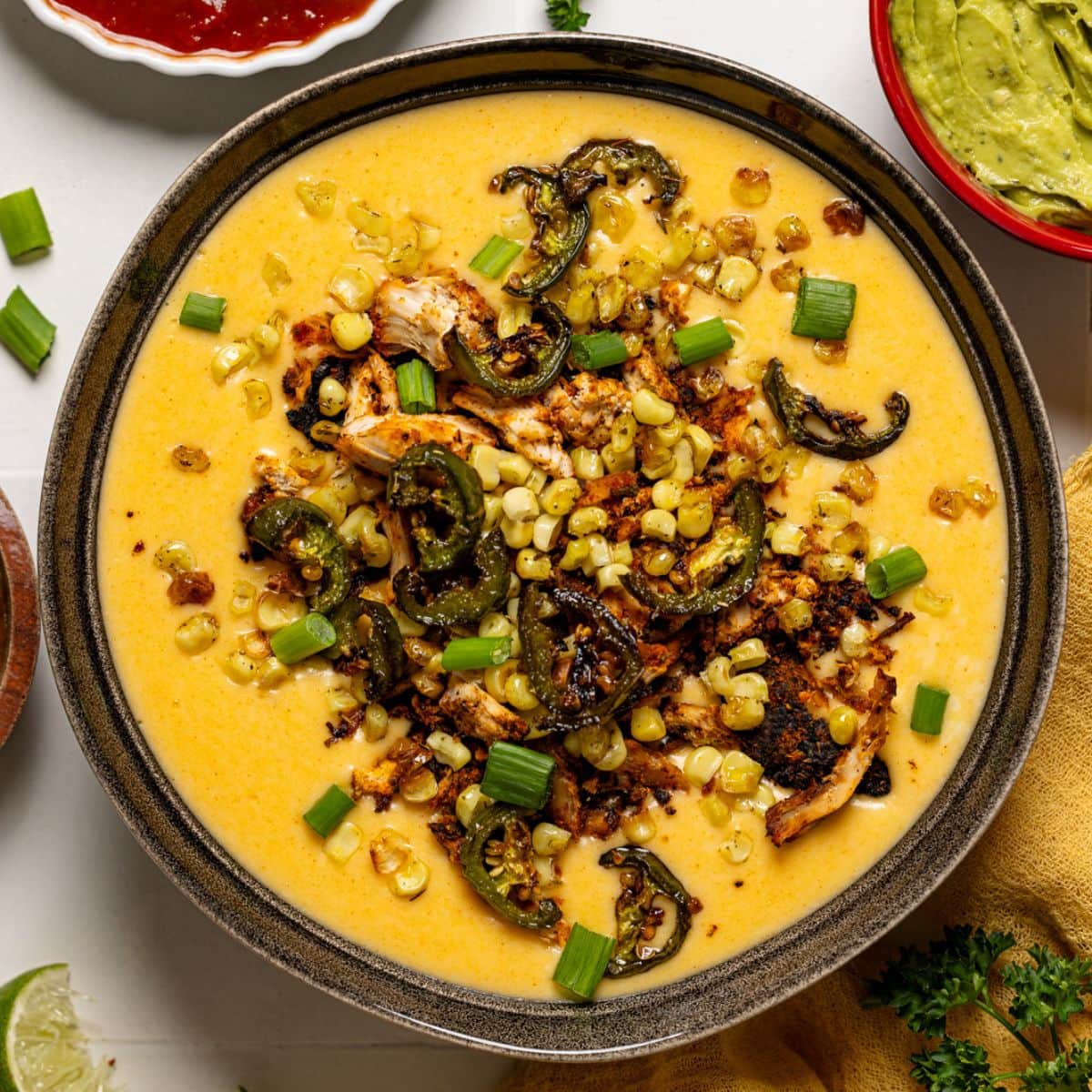 Queso dip with toppings and salsa, guacamole, and lime wedges.