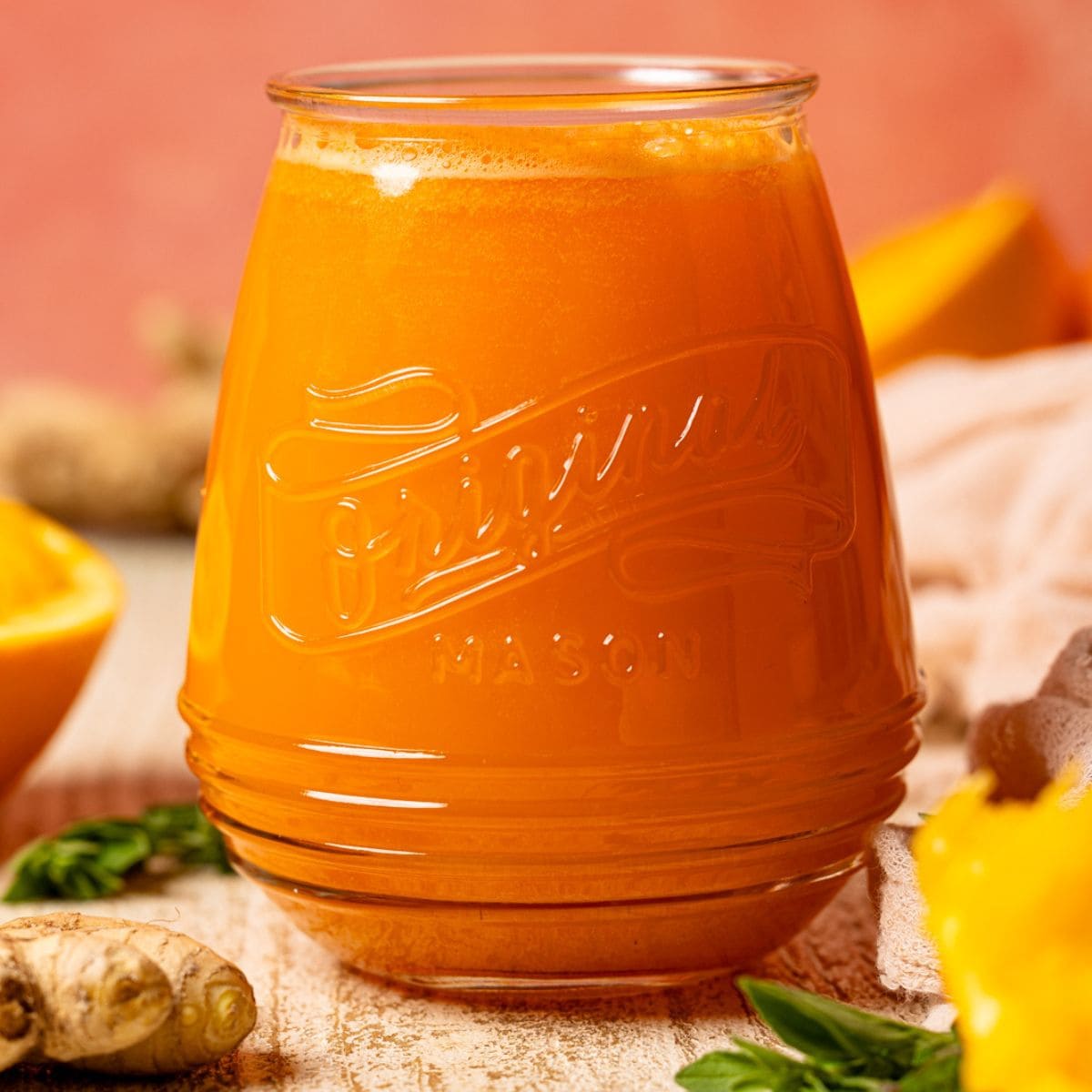 Up close shot of juice in a mason jar with oranges and ginger.