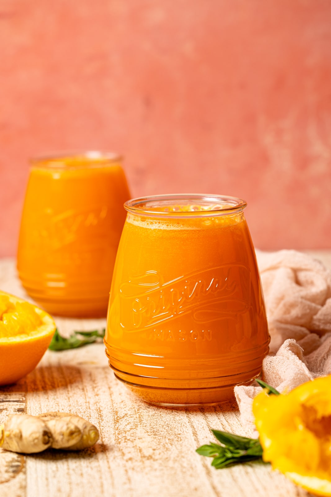 Two mason jars on juice with oranges.