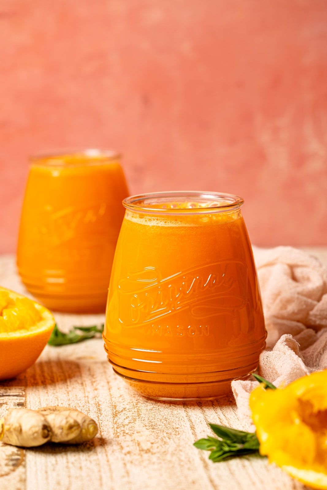 Two mason jars on juice with oranges.