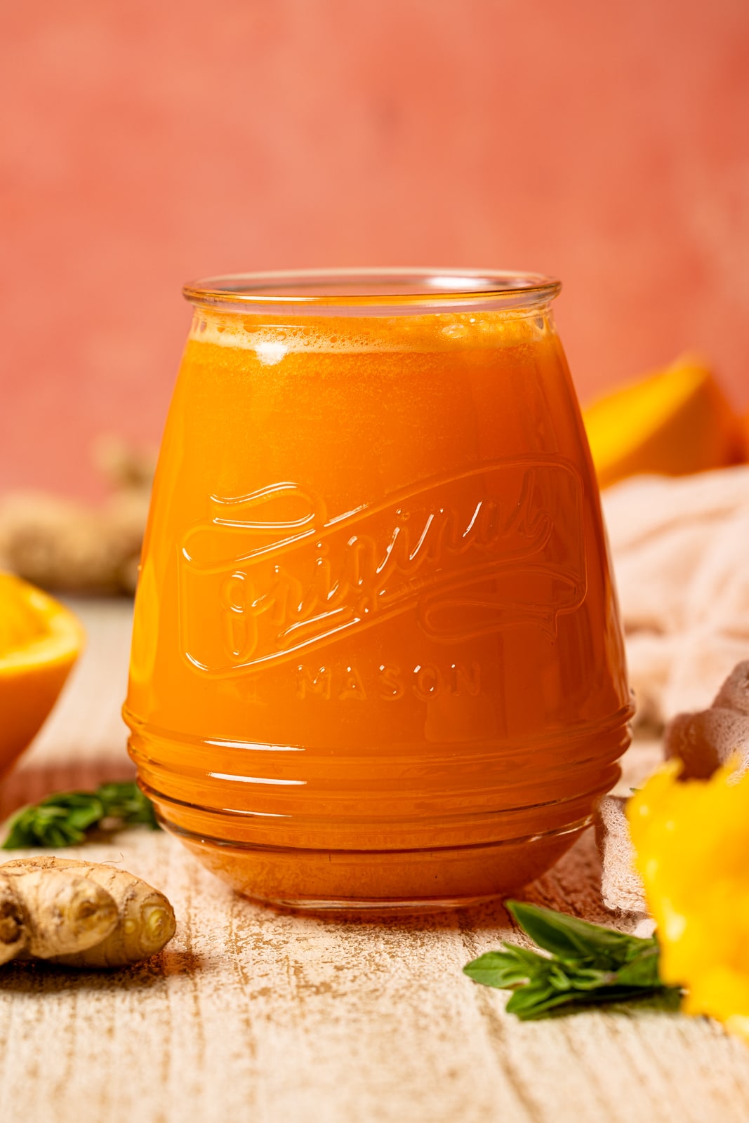 Up close shot of juice in a mason jar with oranges and ginger.