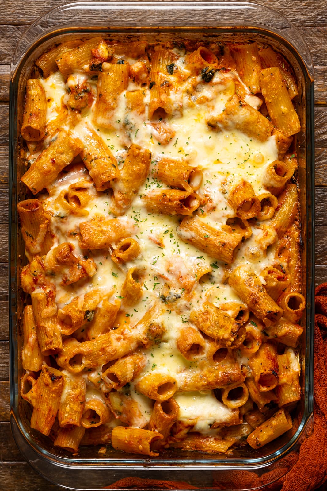Baked pasta in a baking dish on a brown wood table.