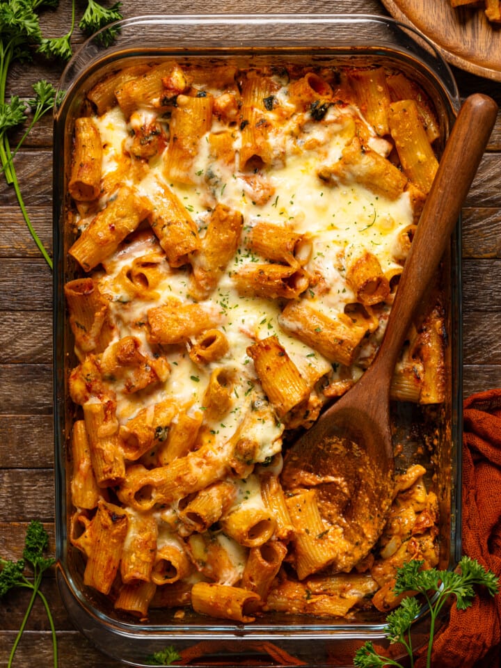 Baked pasta on a wooden brown table with a scoop from a spoon.