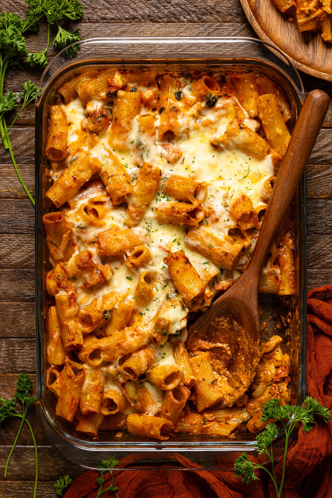 Baked pasta on a wooden brown table with a scoop from a spoon.