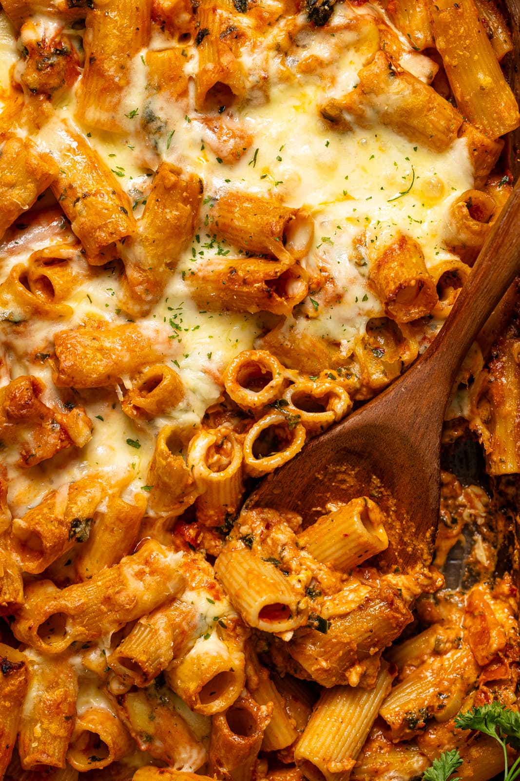 Up close shot of pasta bake with a wooden spoon.