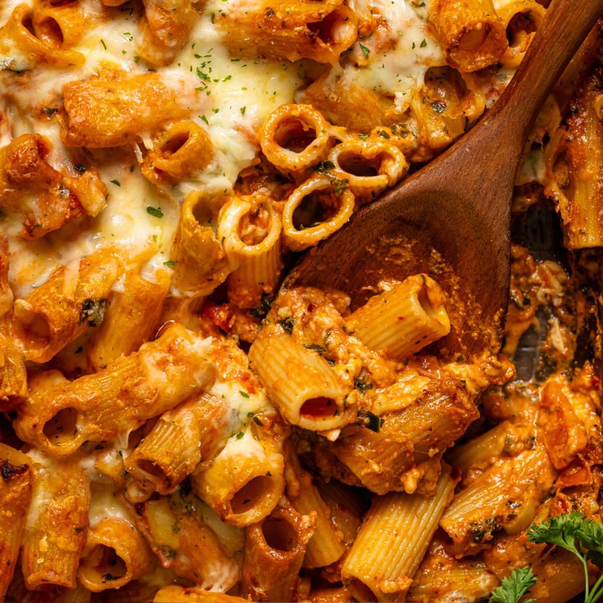Up close shot of pasta bake with a wooden spoon.