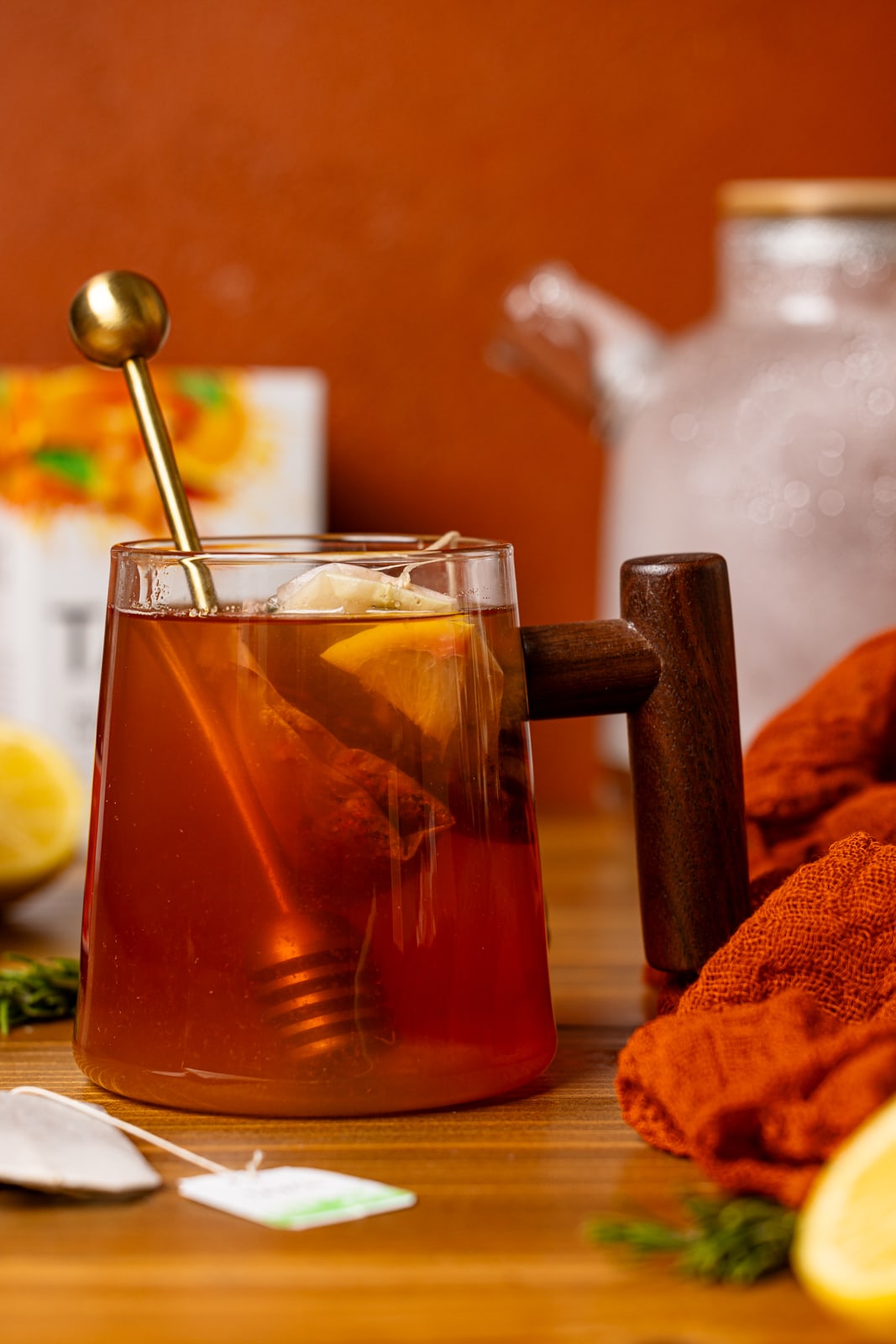 Tea in a glass mug with honey stick and tea boxes.