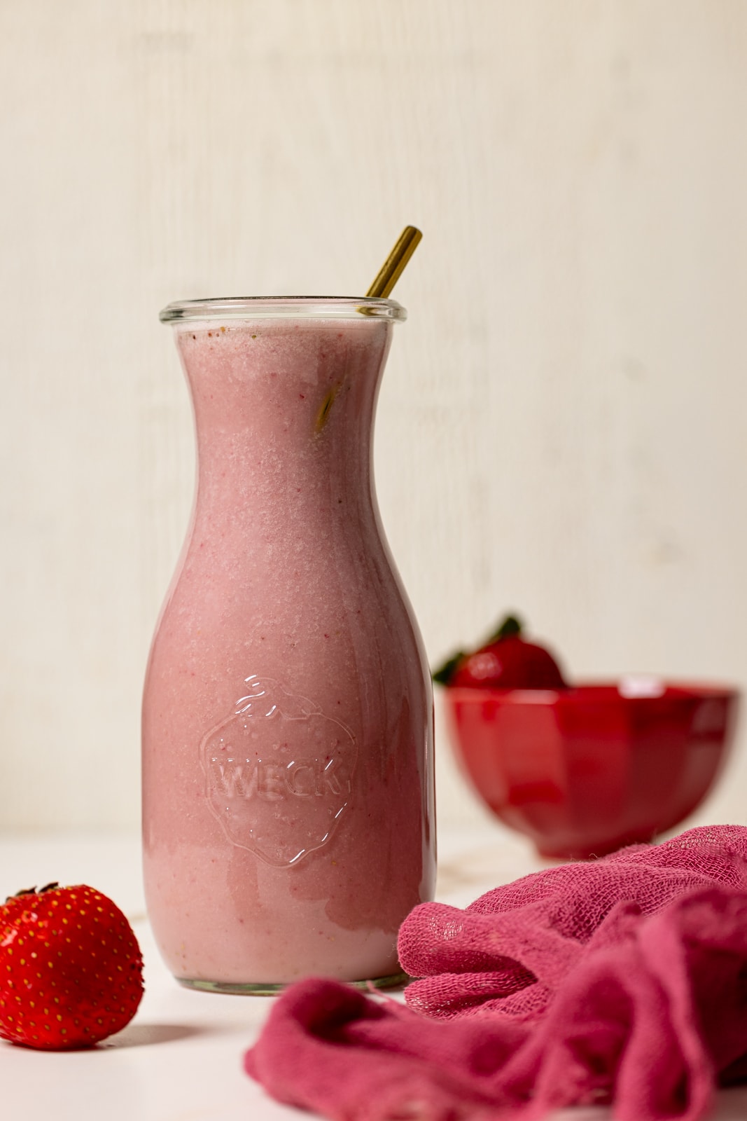 Strawberry milk in a jar with a straw and fresh strawberries.