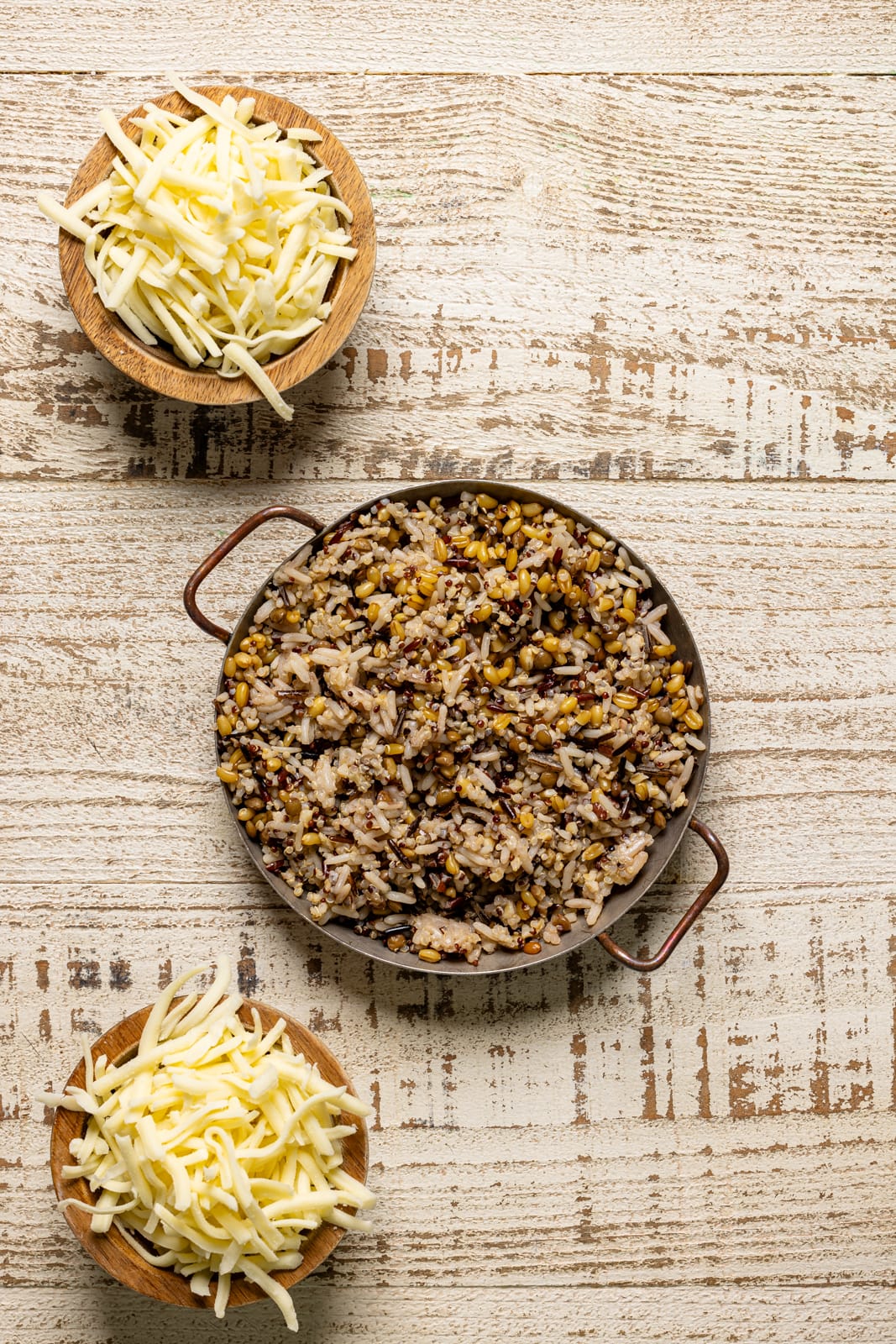 Bowl with quinoa and shredded cheese on a white wood table.