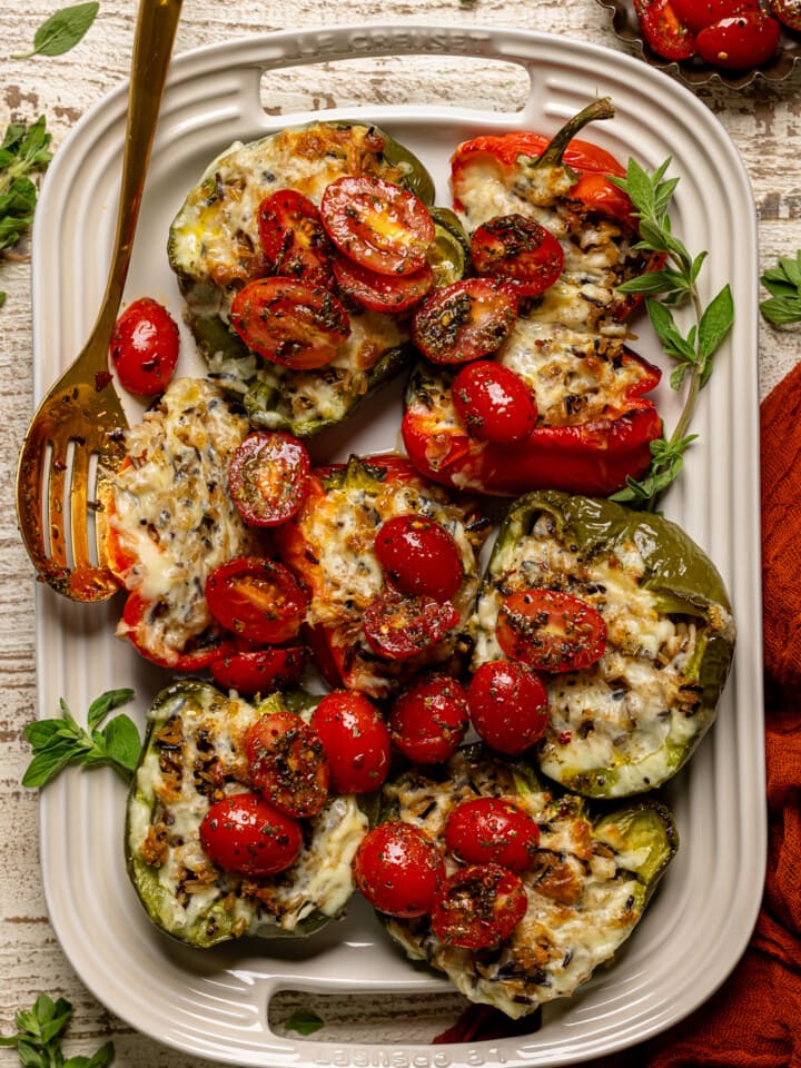 Stuffed peppers on a serving platter with a gold spoon.