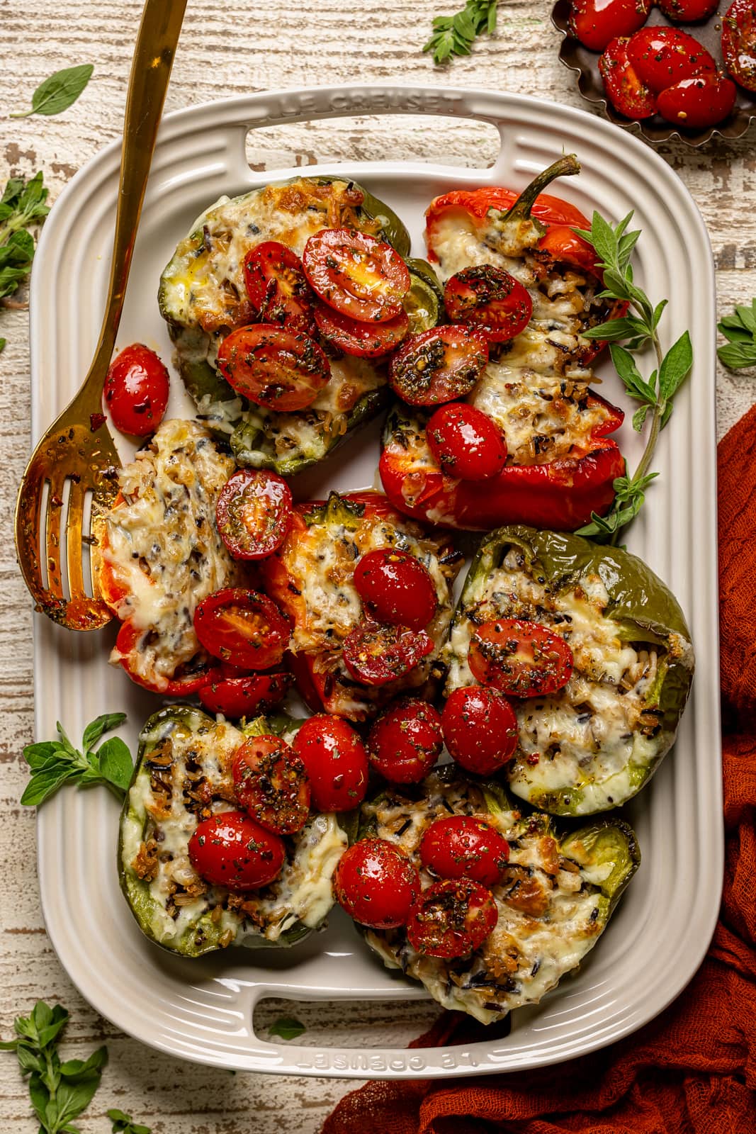 Stuffed peppers on a serving platter with a gold spoon.