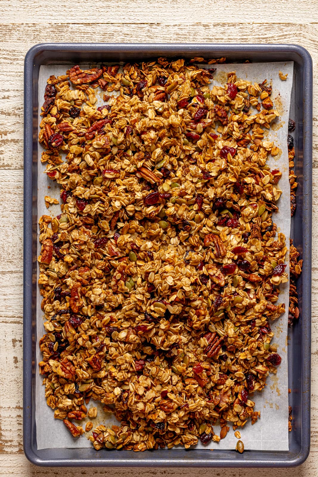 Baked granola on a baking sheet with parchment. 
