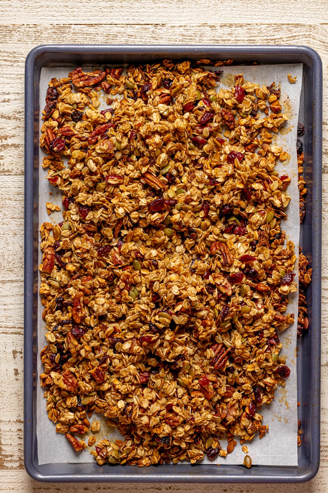 Baked granola on a baking sheet with parchment.