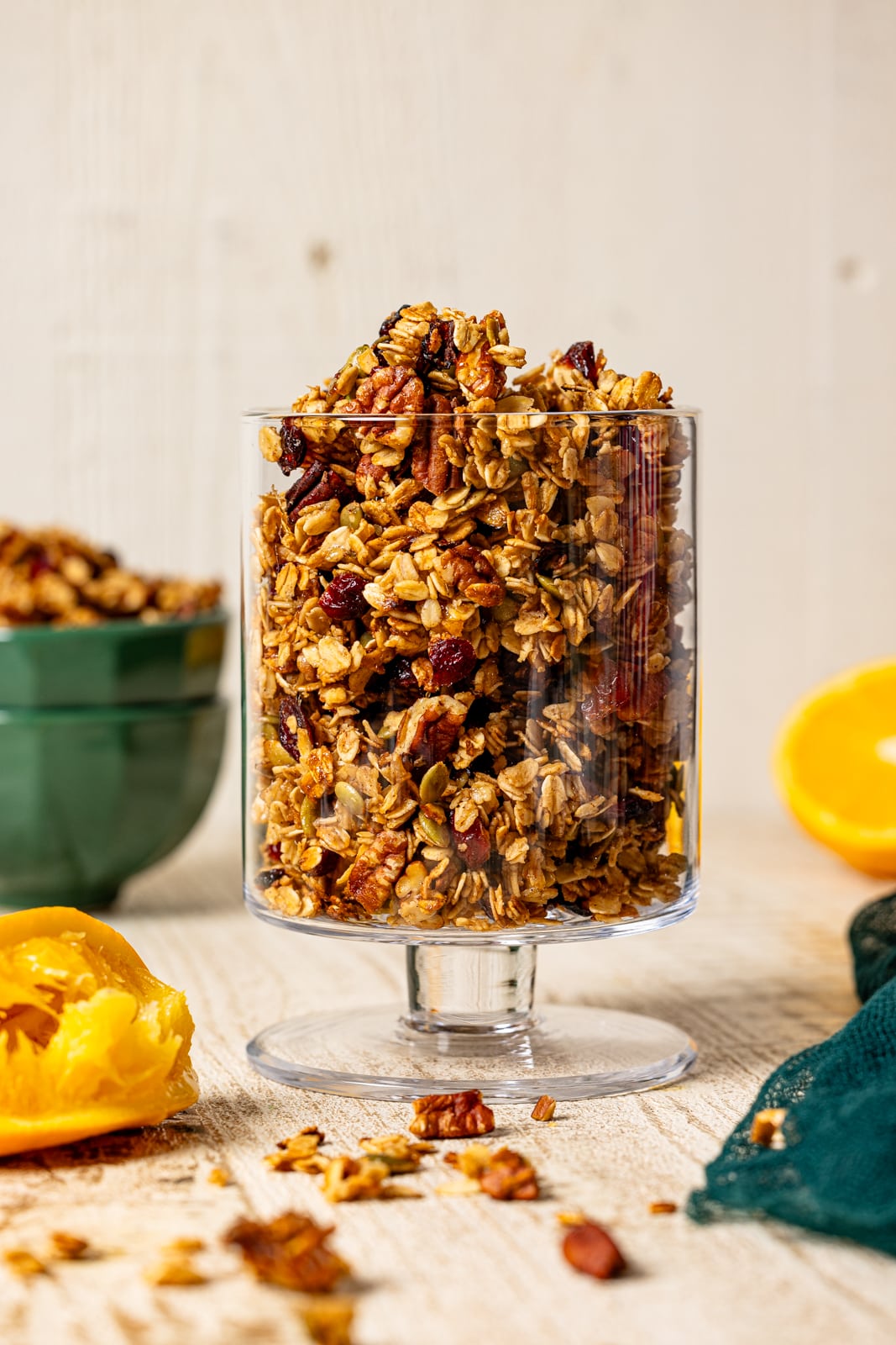 Granola in a clear trifle bowl with oranges. 