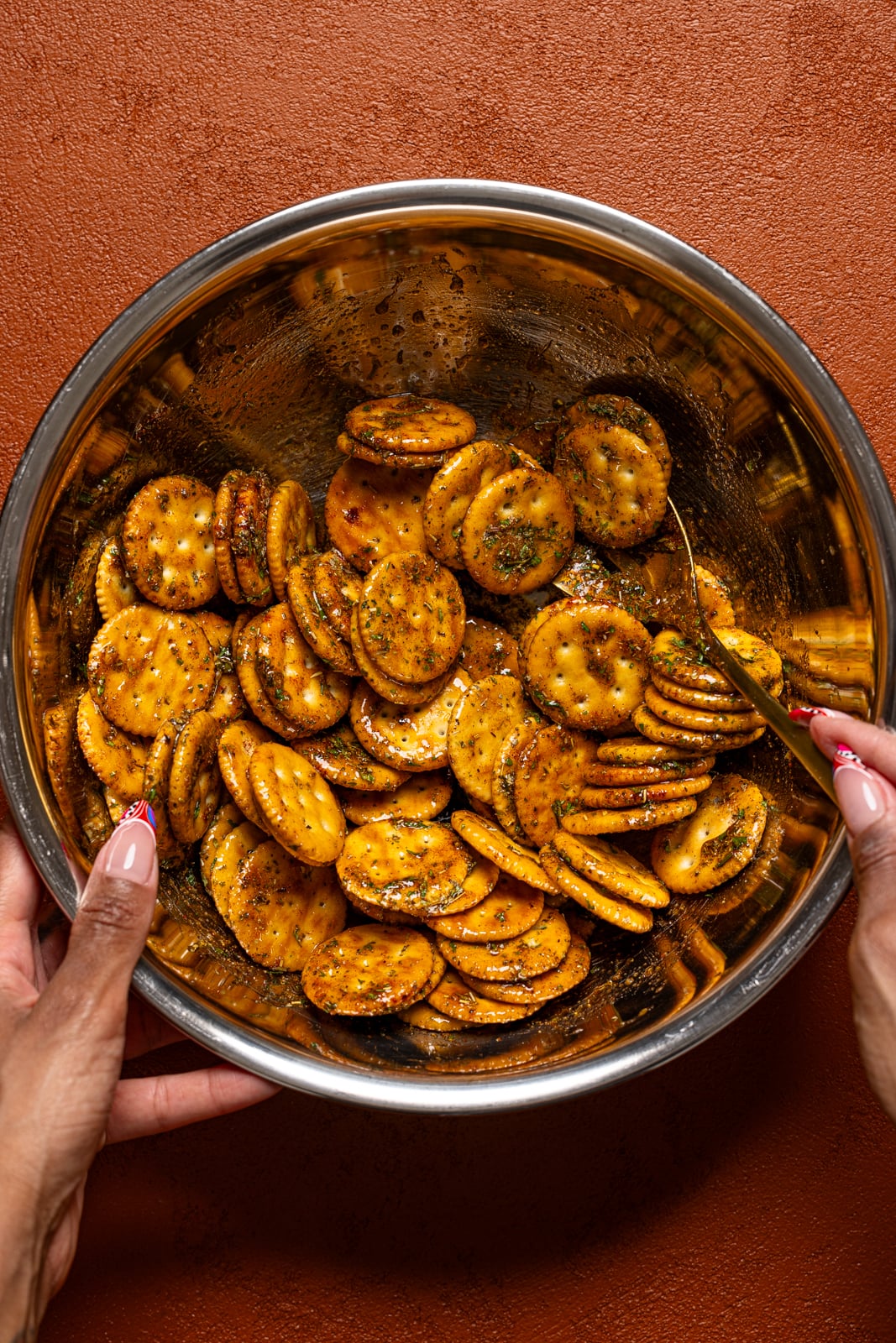 Crackers tossed in seasonings in a silver bowl.