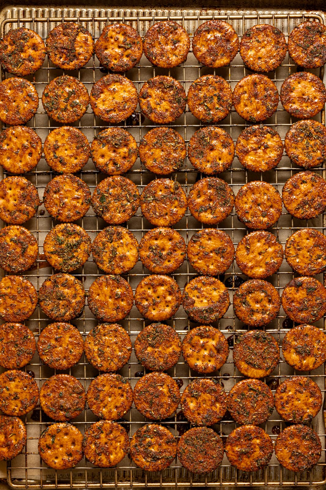 Herbed crackers lined up on a baking sheet with a wire rack.