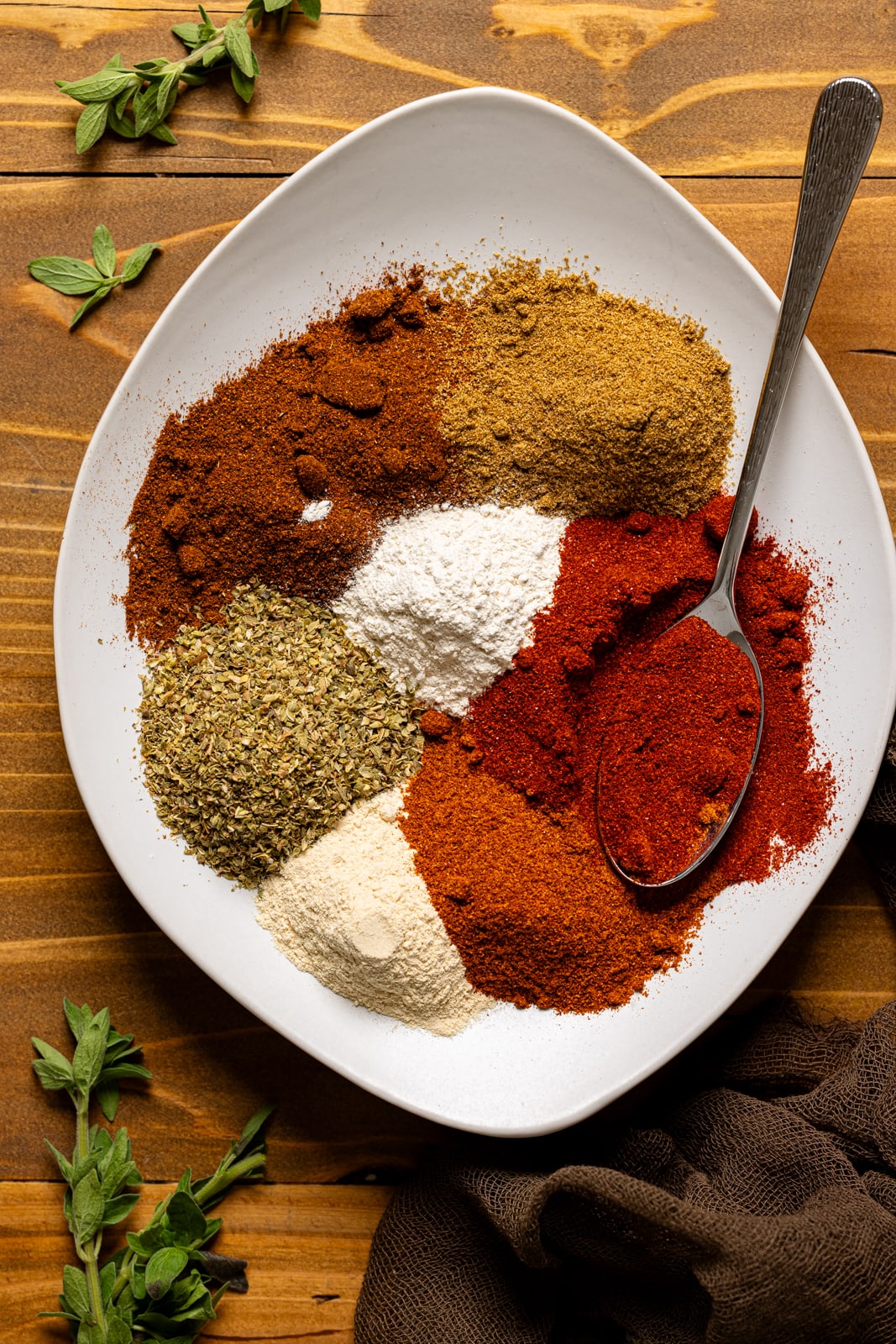 Seasonings individually lined on white plate with a spoon.