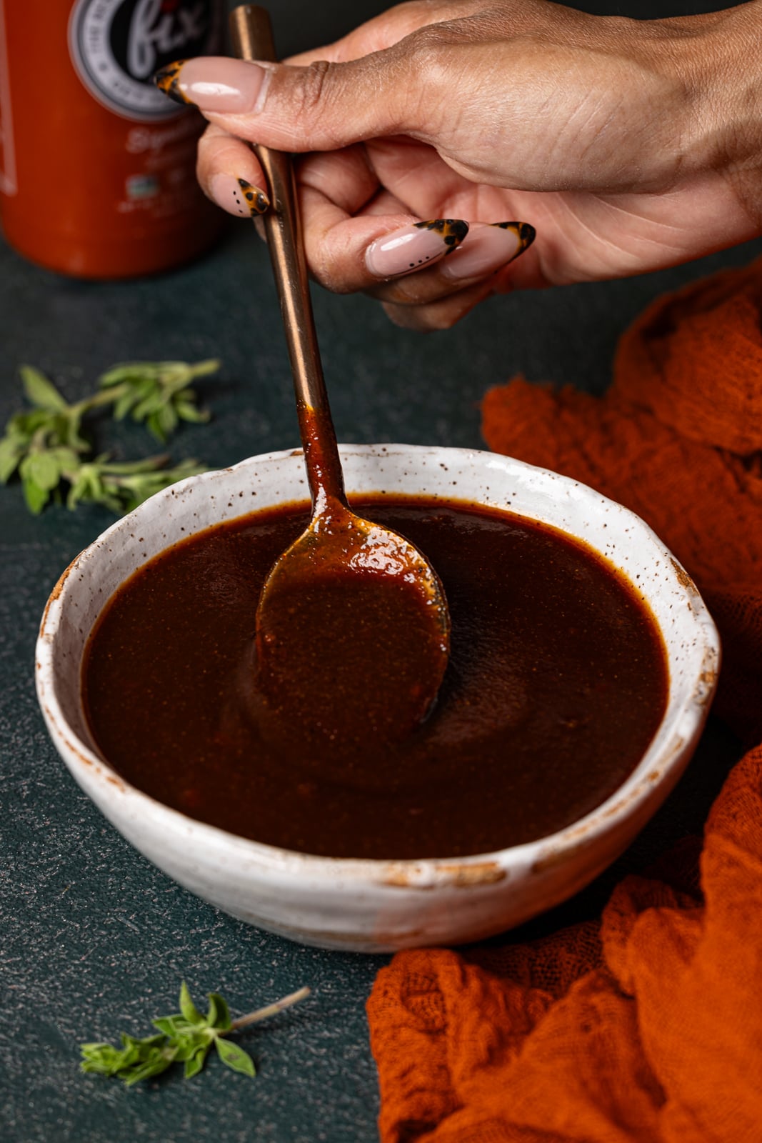 BBQ sauce in a white bowl being held with a spoon.