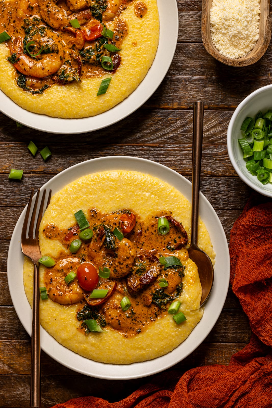 Shrimp and grits with two forks on a brown wood table.