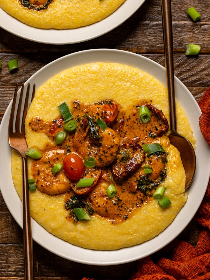 Up close shot of shrimp and grits with a spoon and fork.