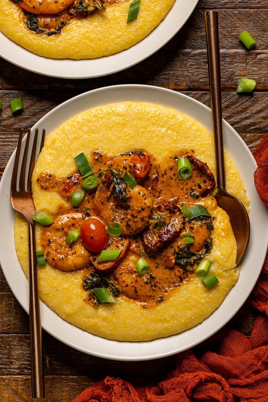 Up close shot of shrimp and grits with a spoon and fork.