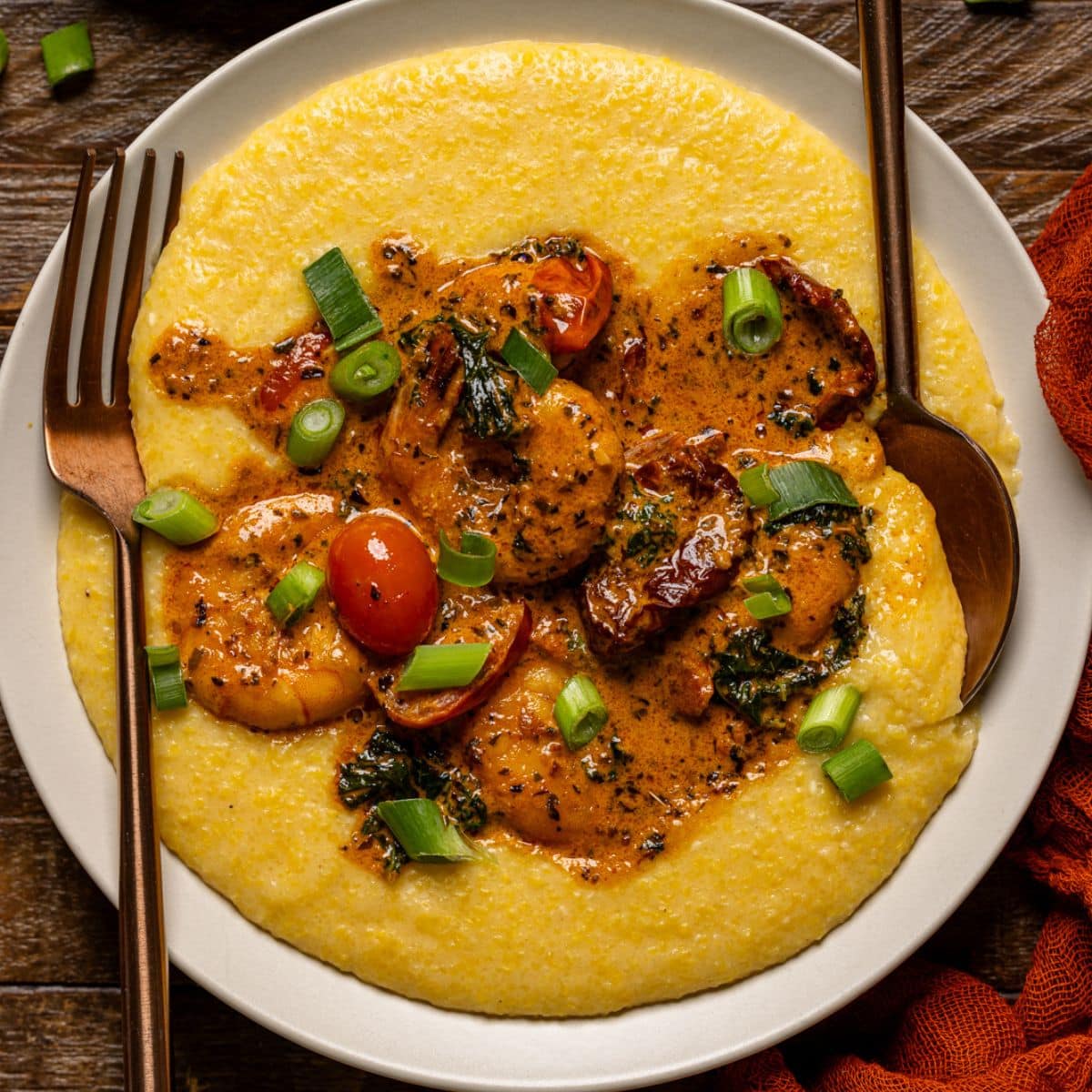 Up close shot of shrimp and grits with a spoon and fork.