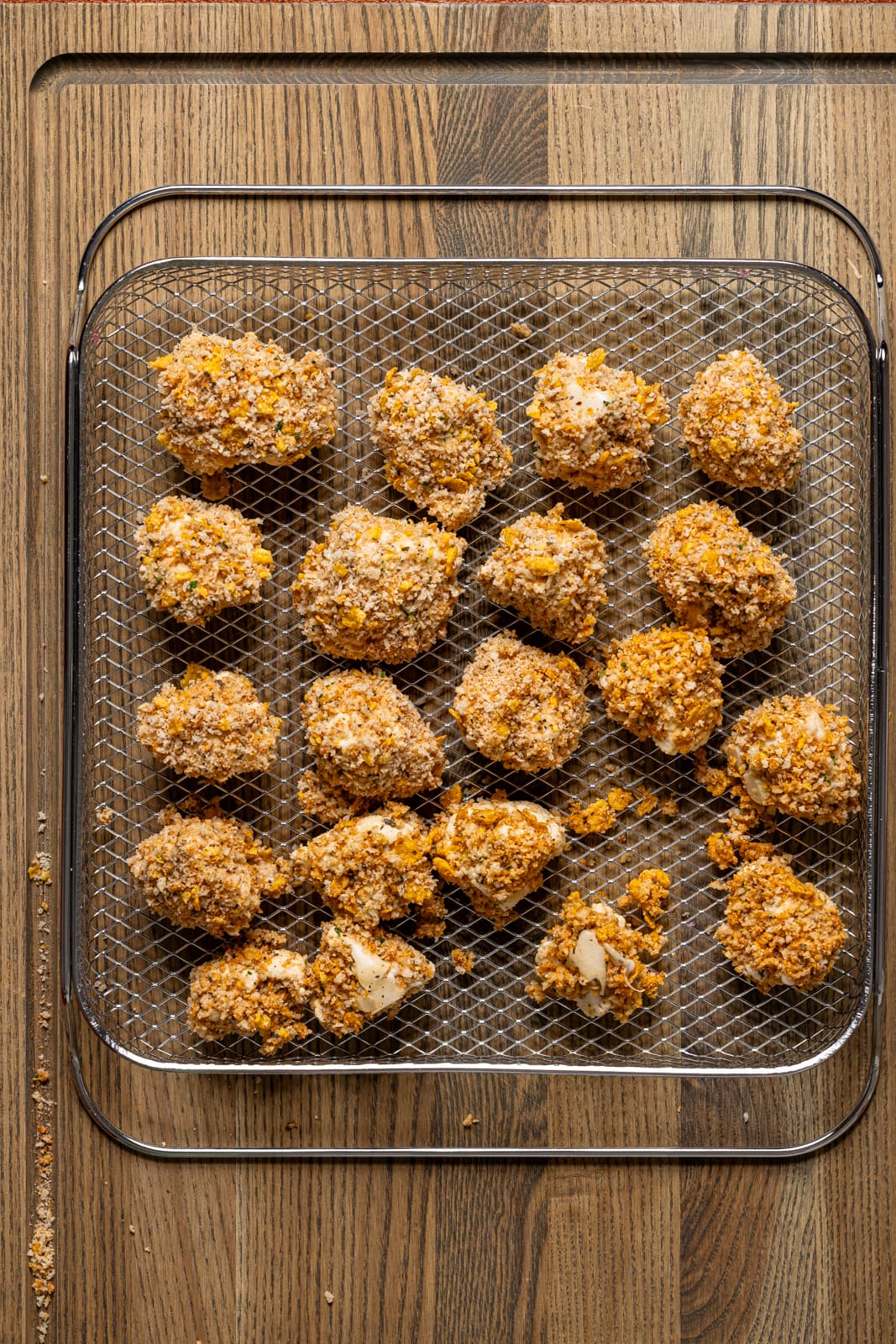 Coated cauliflower on a Air Fryer basket.