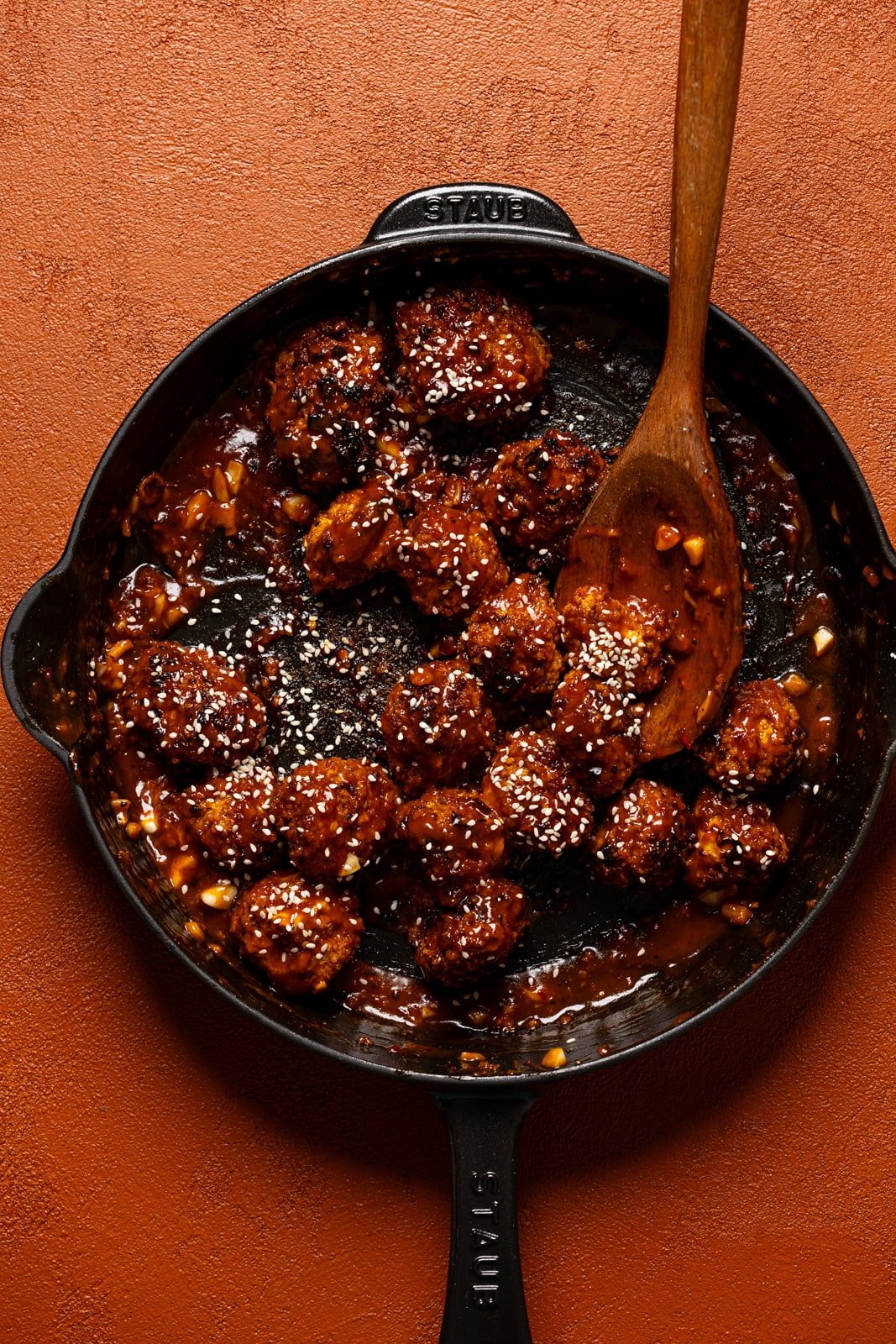 Plant based General Tso, chicken in a skillet with a wooden spoon.