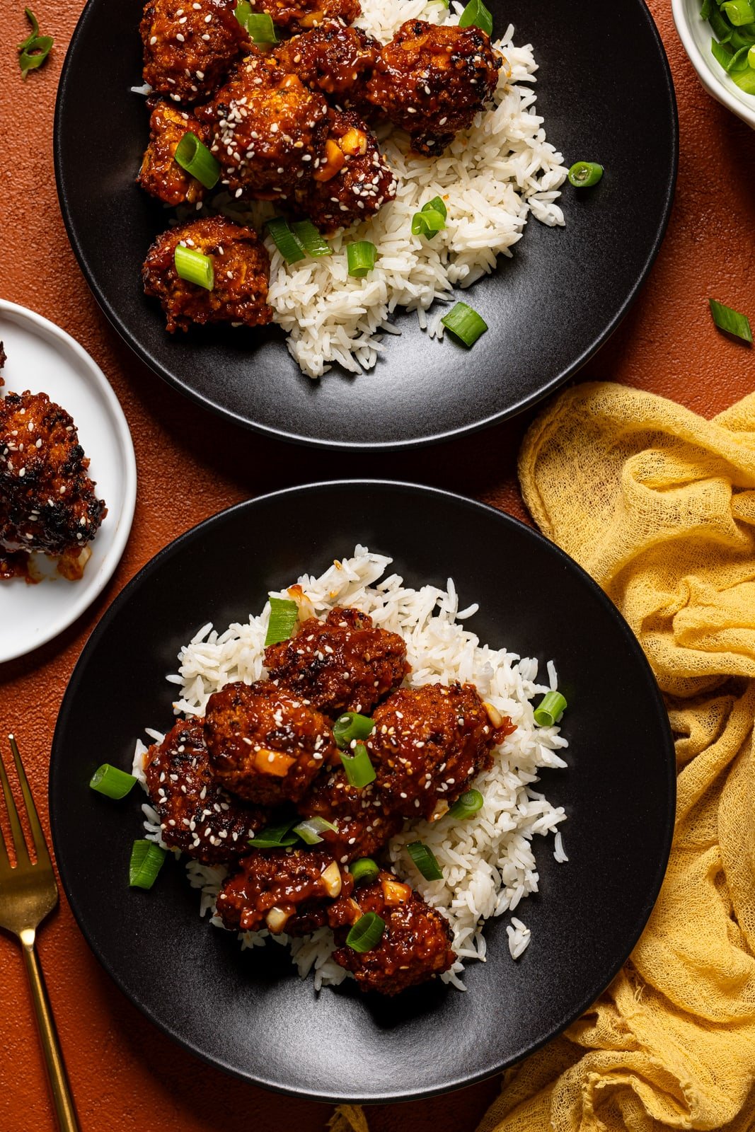 General tso' chicken on two black plates with a yellow napkin.