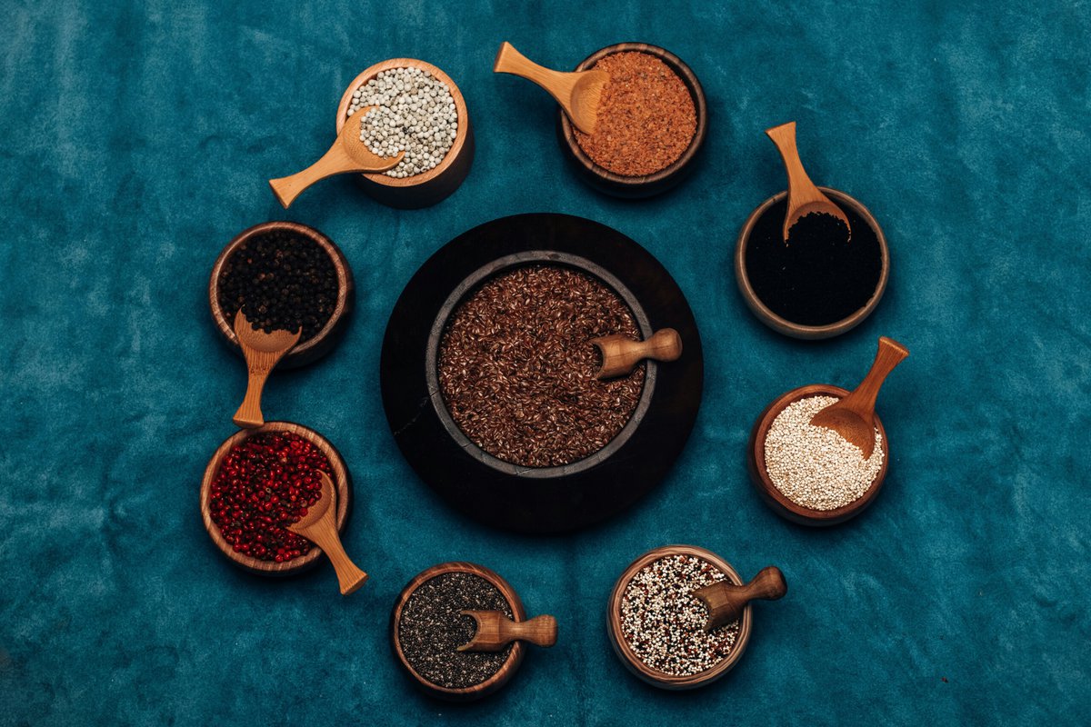 Seeds in small wooden bowls on a blue background.