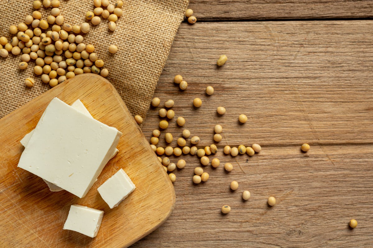 Tofu and soybeans on a wooden table and chopping board.