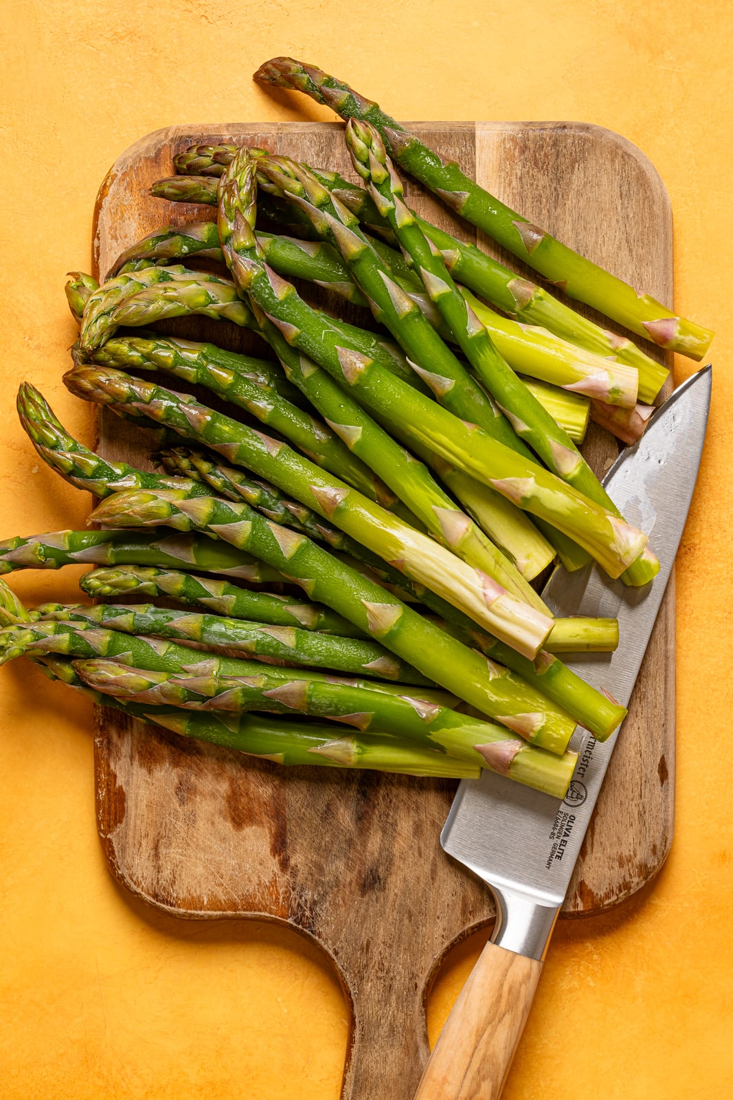 Asparagus on a cutting board with a knife.