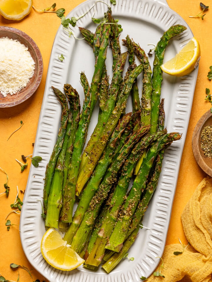 Asparagus on a platter with lemon slices and garnish.