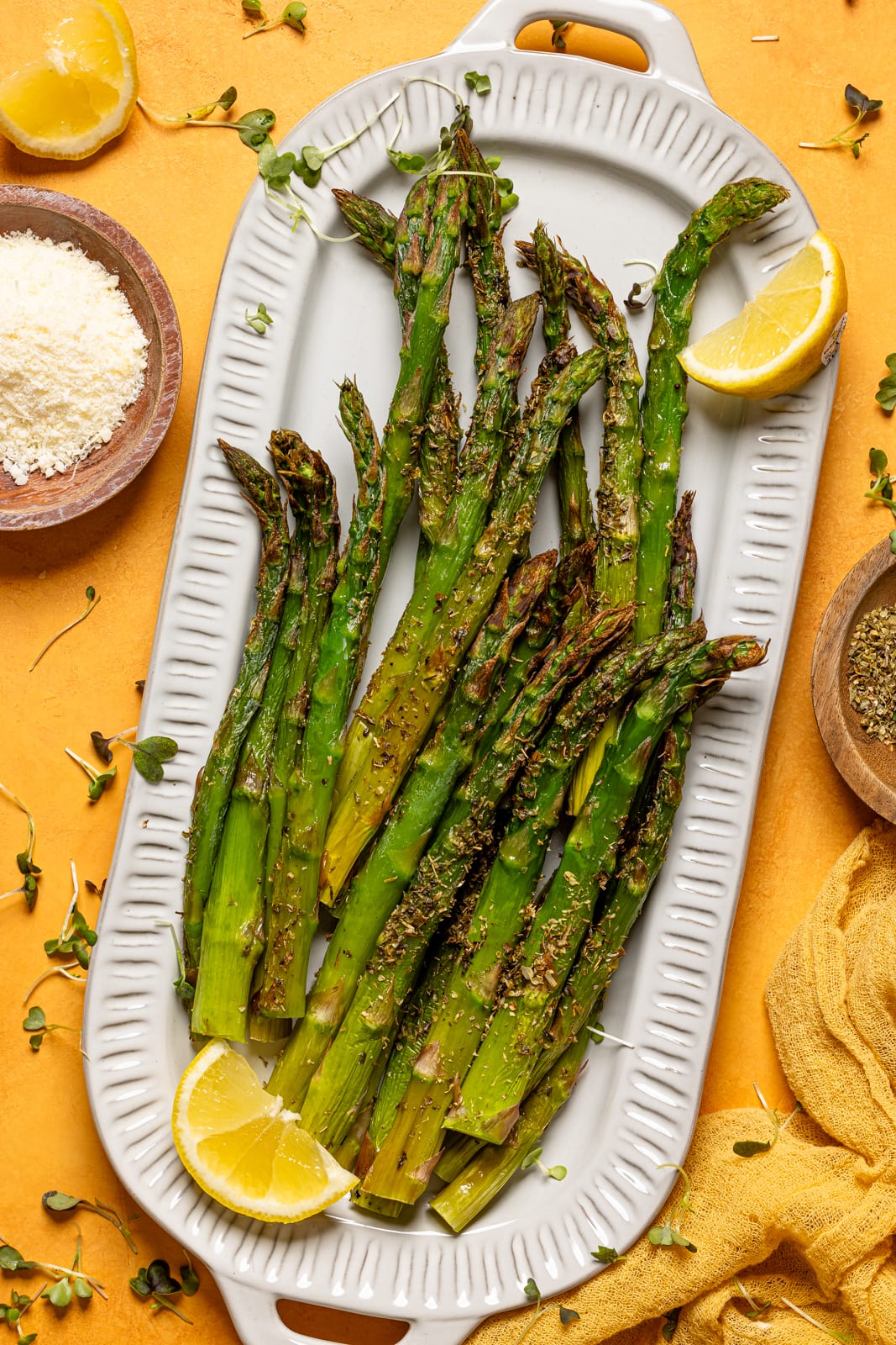 Asparagus on a platter with lemon slices and garnish.