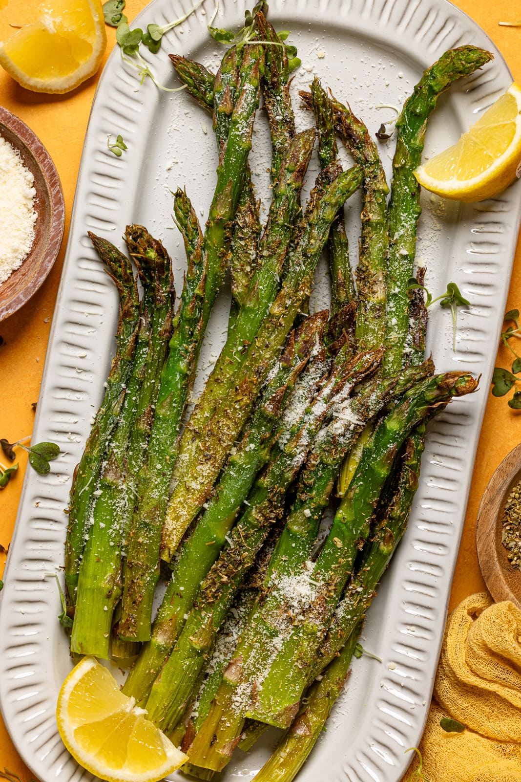 Up close shot of asparagus on a platter with lemons.