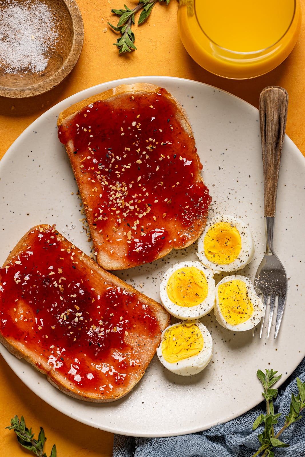 Eggs with jam toast on a plate with a fork and drink.