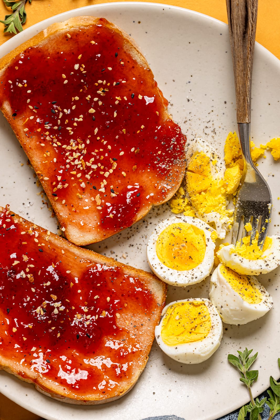Hard boiled eggs on a plate with jelly toast and a fork.