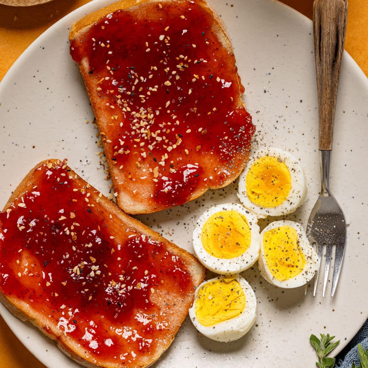 Eggs with jam toast on a plate with a fork and drink.