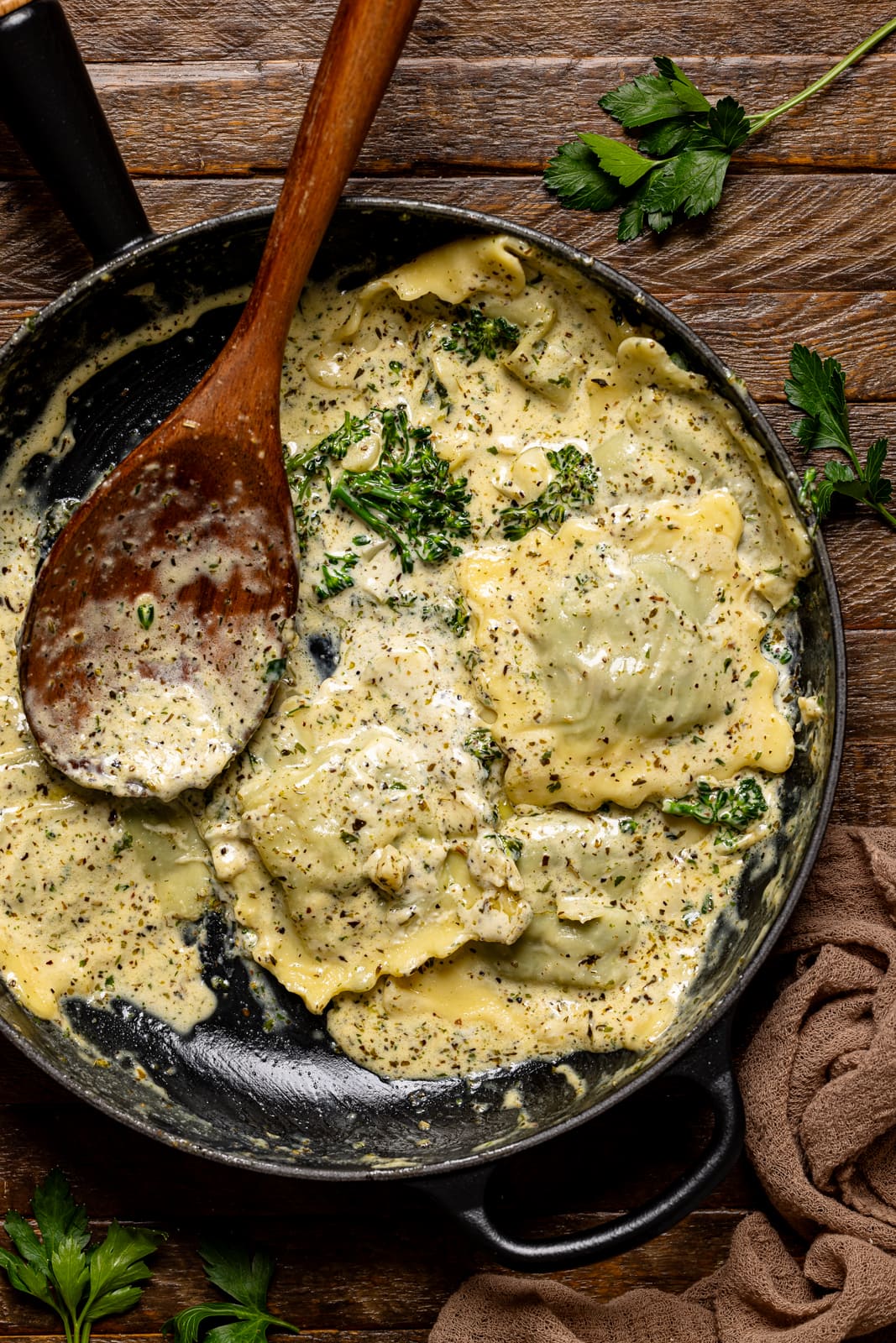 Ravioli in a black skillet with a brown wooden spoon.
