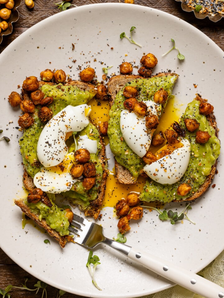 Avocado toast with a fork on a white plate.