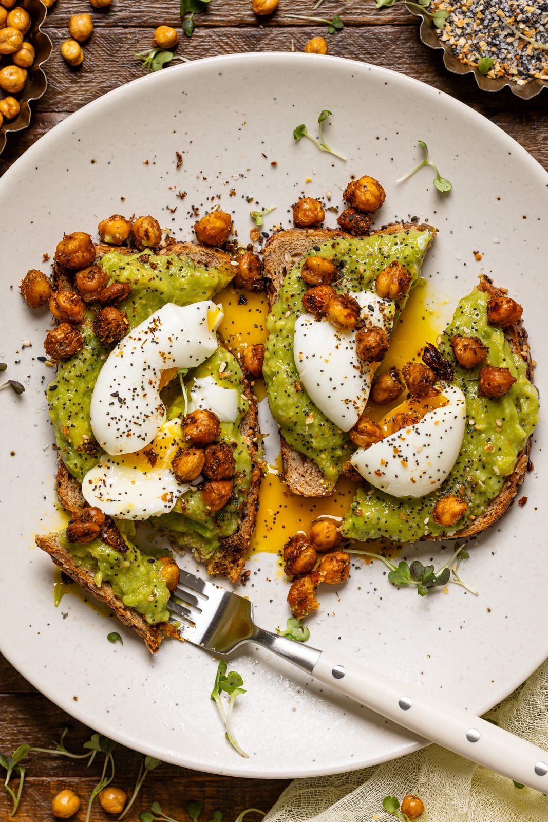 Avocado toast with a fork on a white plate.